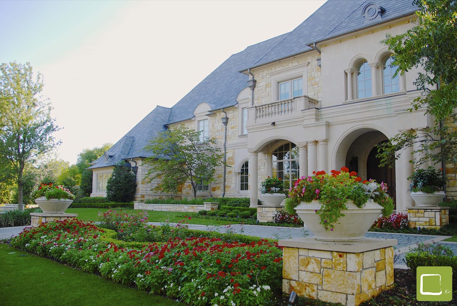 Formal auto court entry with stone planters in Dallas by landscape design firm